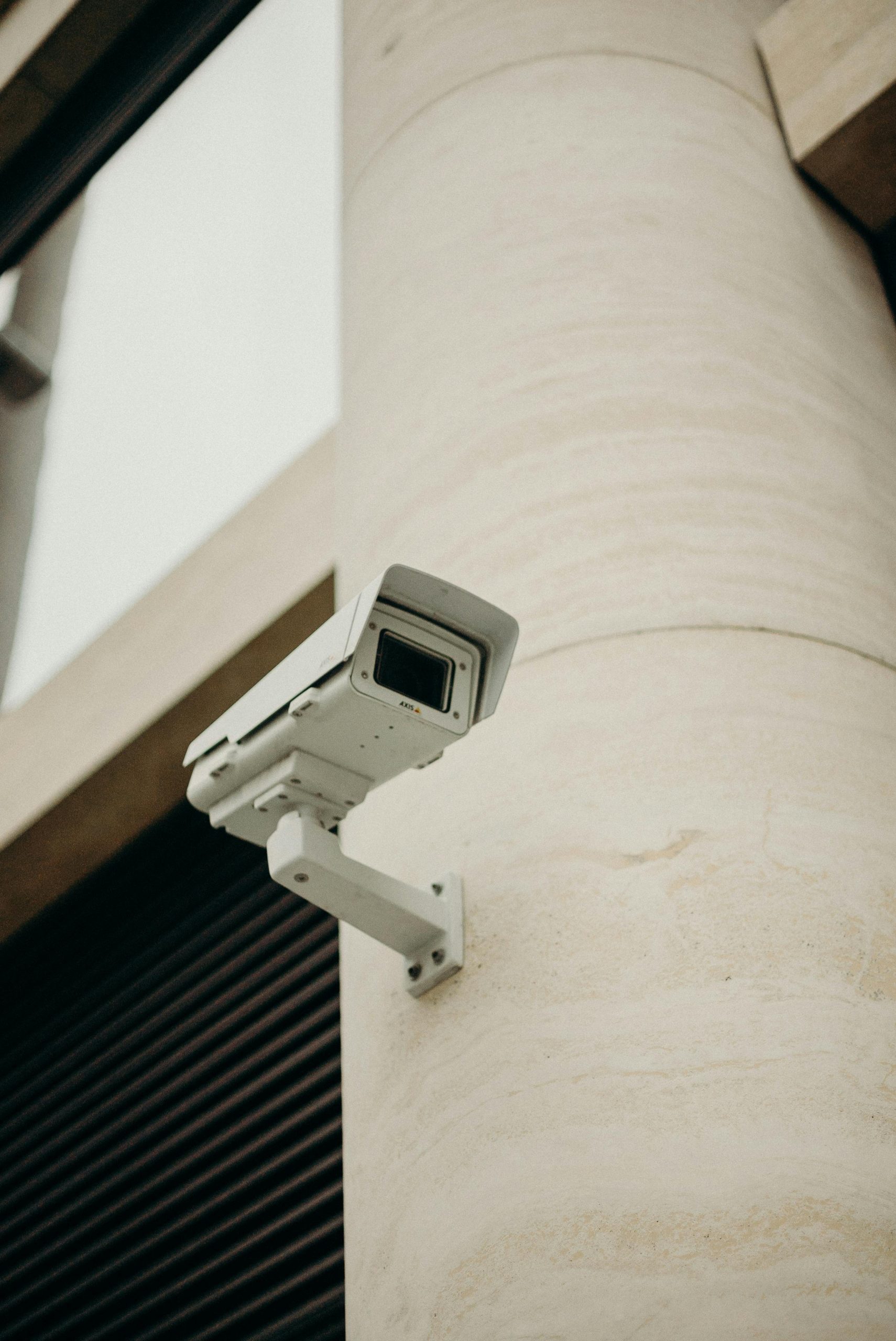 Close-up of a CCTV camera on a concrete building, symbolizing security and technology.